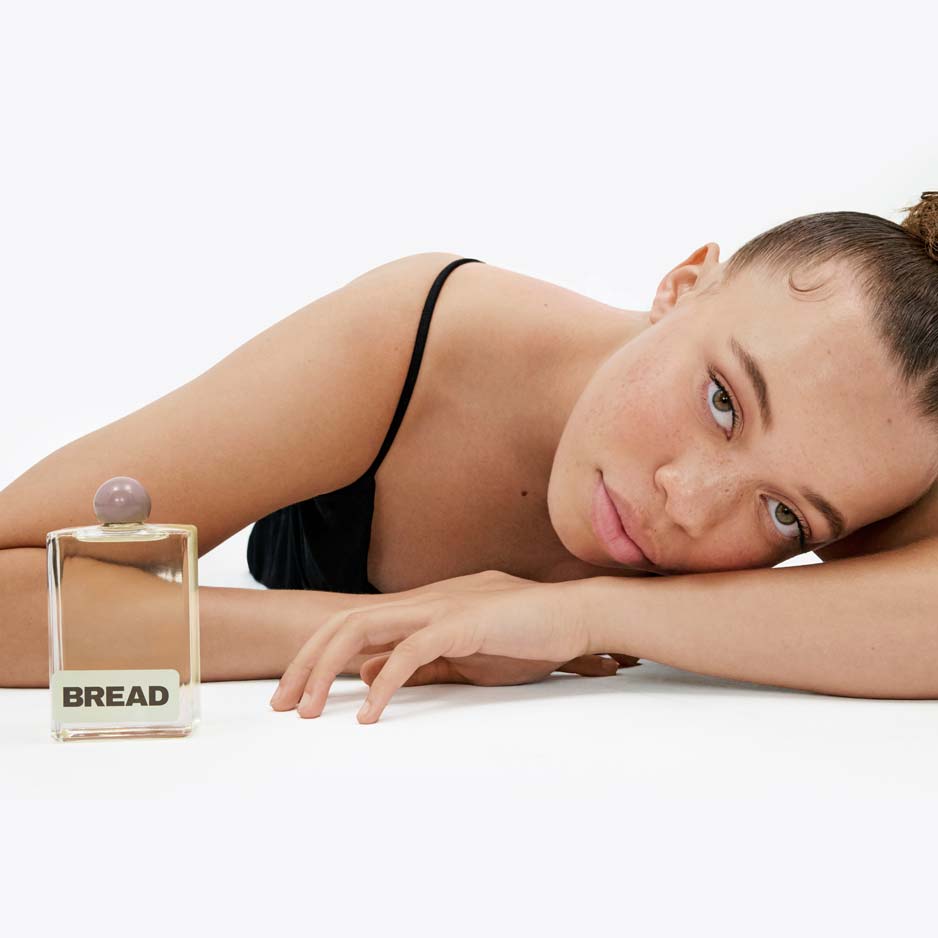 Woman resting her head on her arm with Bread Beauty Hair Oil.